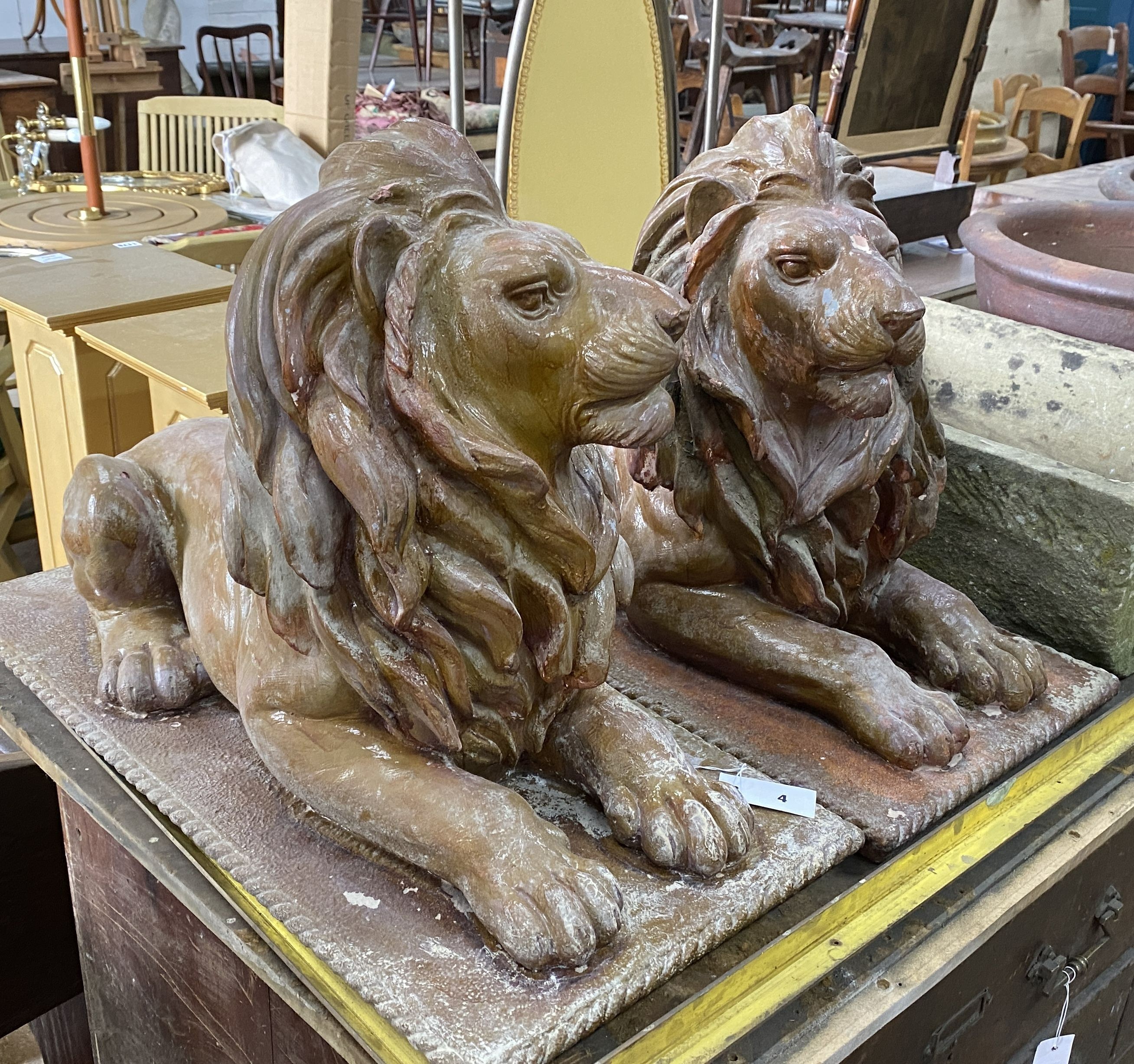 A pair of faux terracotta resin recumbent lion garden ornaments, length 74cm, width 36cm, height 50cm